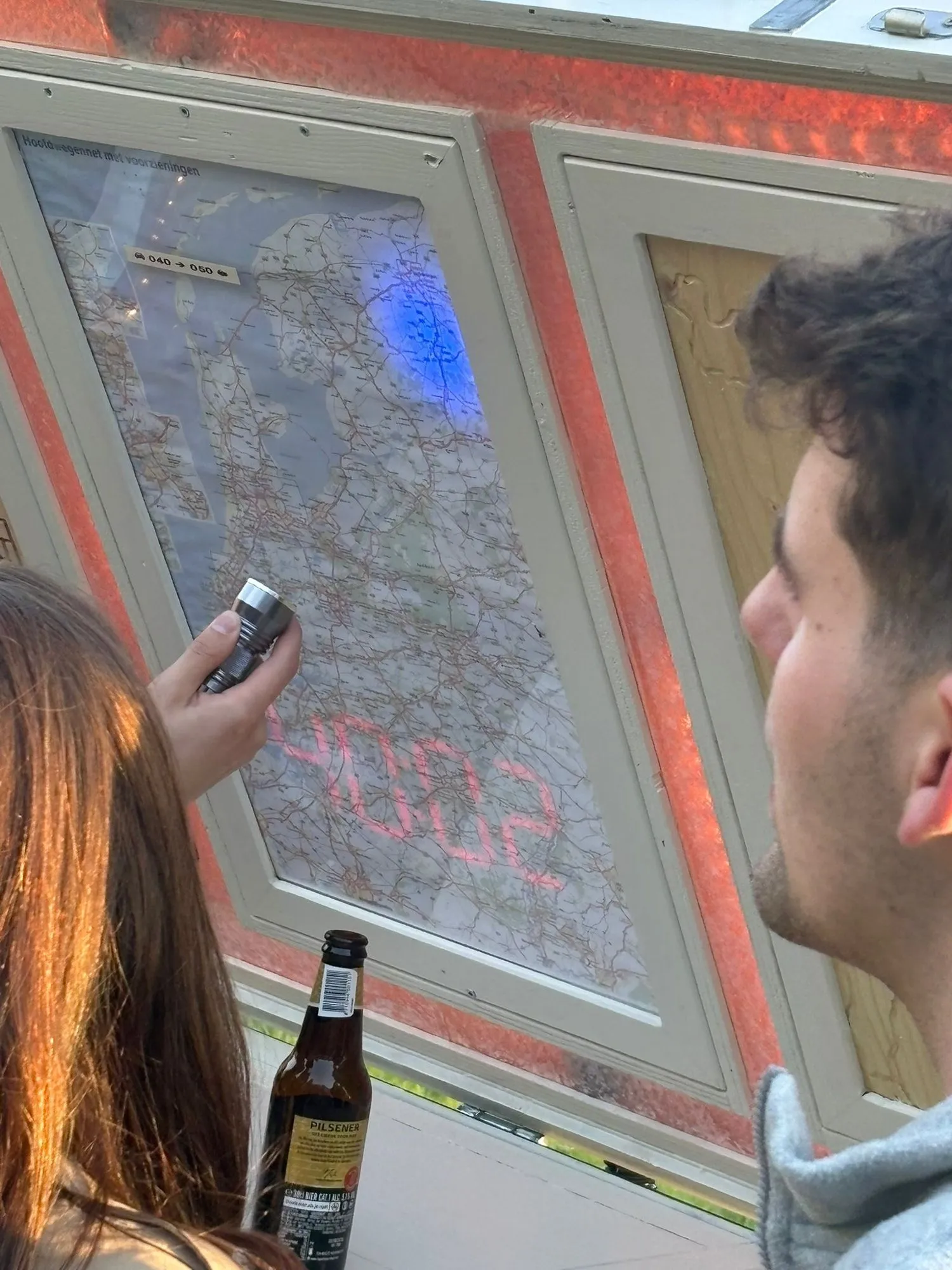 Een speler schijnt met een lamp op de landkaart in de escape trailer op zoek naar aanwijzingen